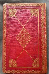 Photo of the right-hand board of a book, covered in red goat skin and elaborately decorated with gold tools